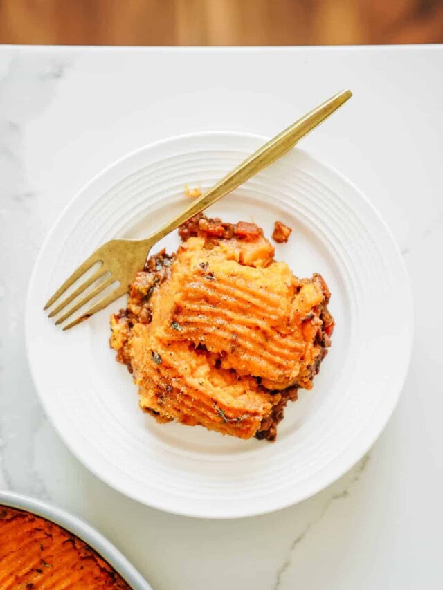 A slice of Vegan Shepherd's Pie sitting on white plate with gold fork.