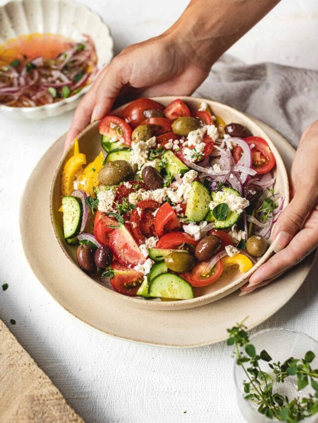 Greek salad being place on counter