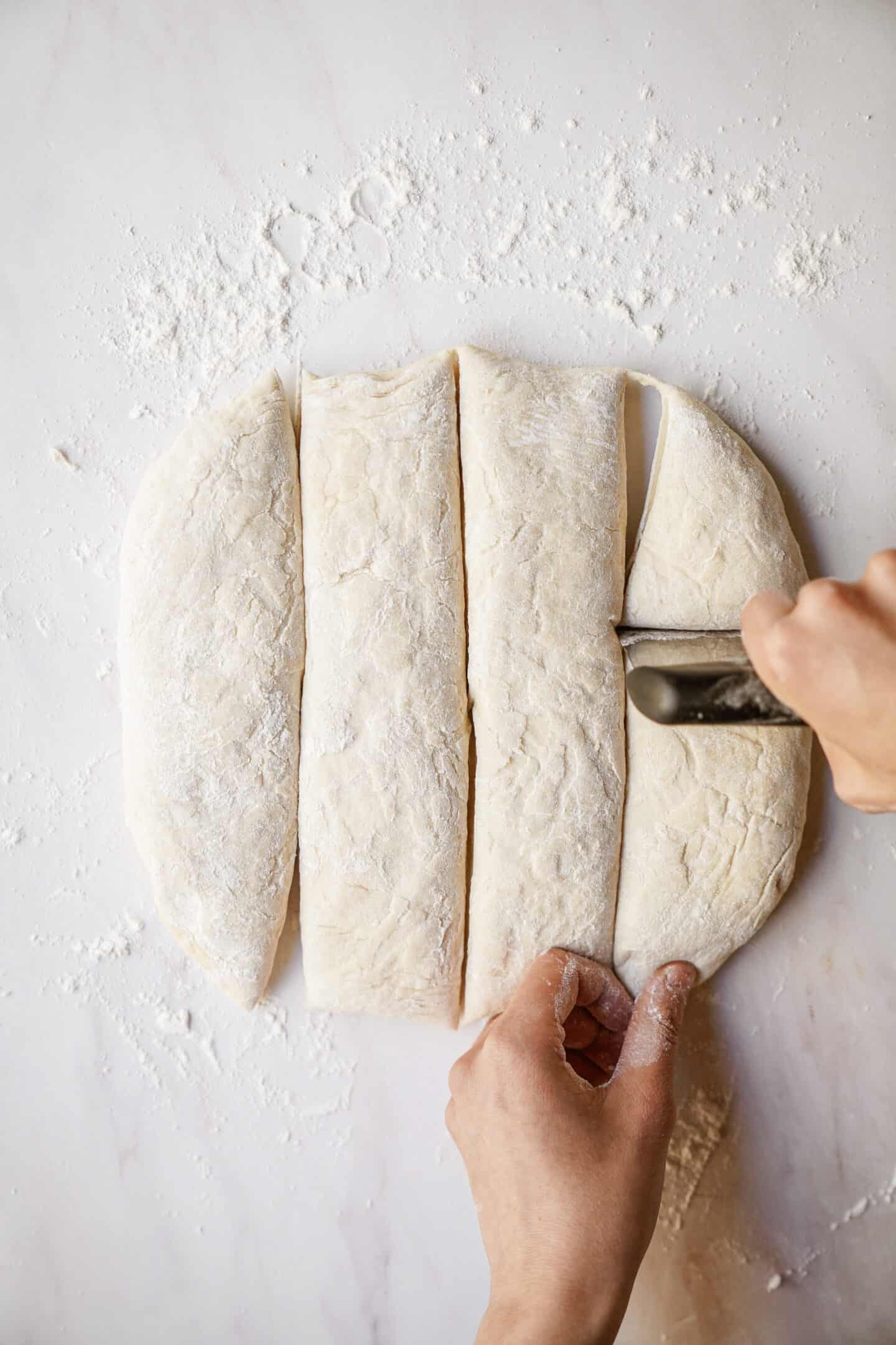 Dinner roll dough being cut into squares