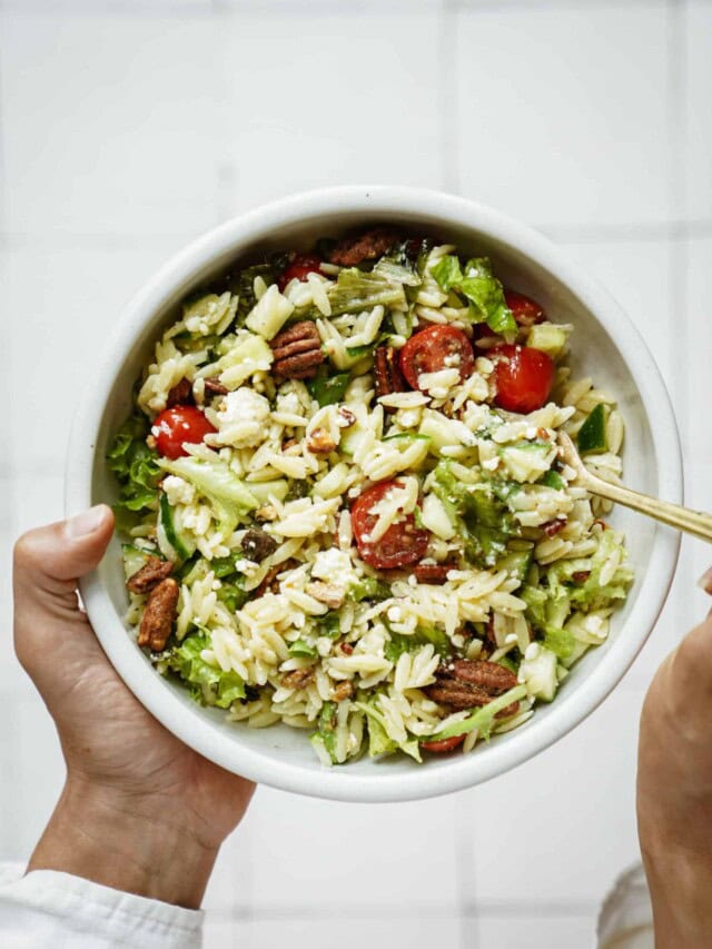 Hand holding a summer salad with a spoon