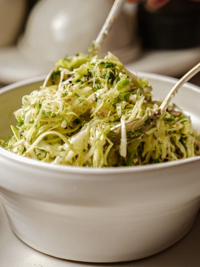 Bowl of Greek cabbage salad with serving spoons in it