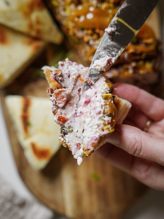 Cheese log being spread on bread