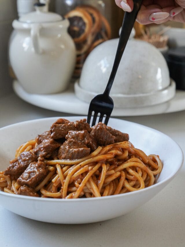 Close up of a fork spinning the noodles in a beef stew