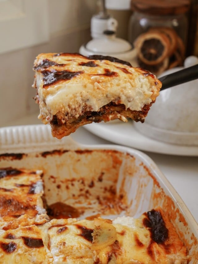 Greek Moussaka being taken out of a baking dish