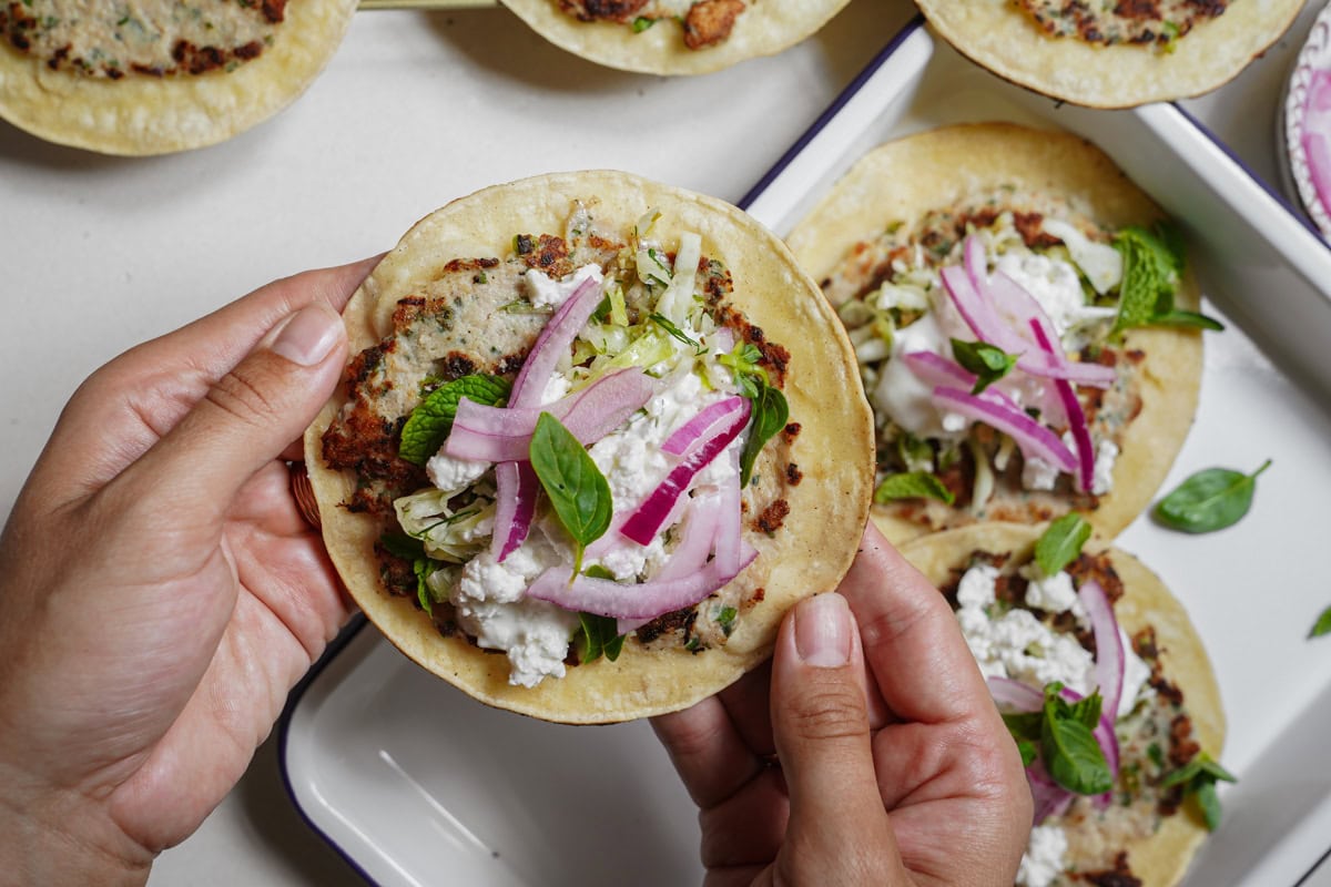 Hands holding smashed burger taco