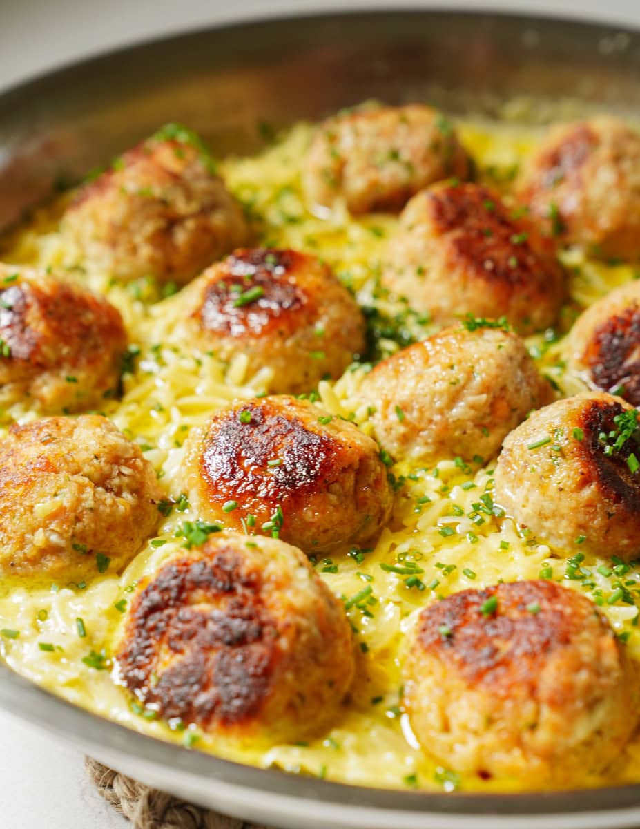 In a pan cooks 13 steelhead trout balls simmering in creamy yellow orzo