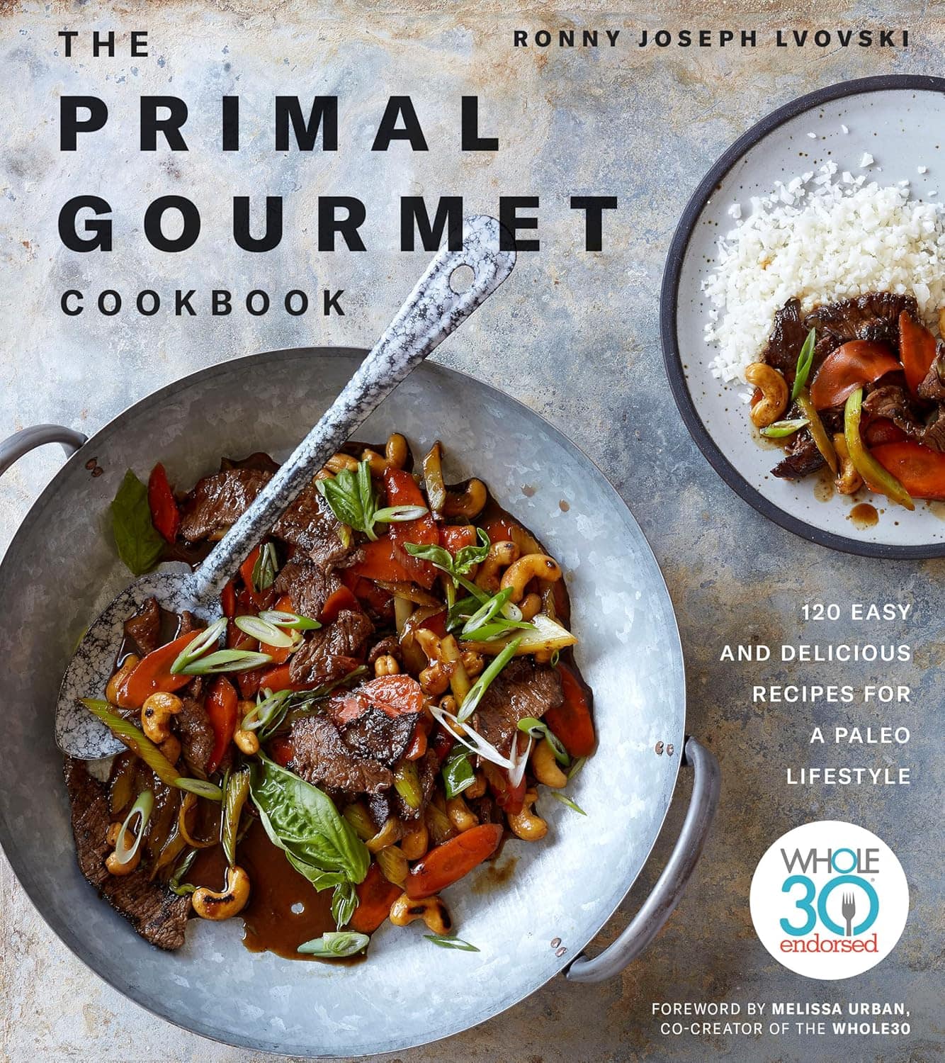 Cover of The Primal Gourmet Cookbook by Ronny Joseph Lvovski. Features a skillet with a beef stir-fry dish and vegetables, alongside the book title and author. Includes a note about 120 recipes for a paleo lifestyle and a Whole30 endorsement.