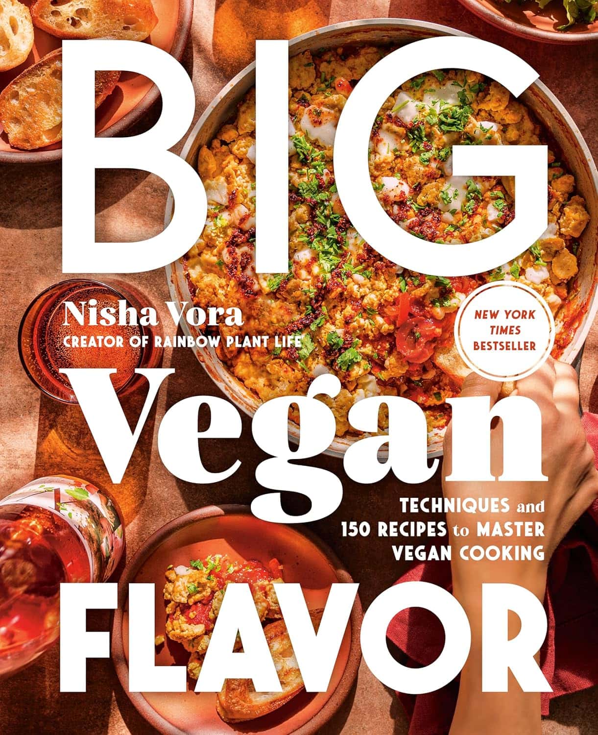 Cookbook cover titled Big Vegan Flavor by Nisha Vora. The cover features a colorful dish of vegan food with chopped vegetables. There are text mentions of techniques and 150 recipes, and a note indicating it is a New York Times bestseller.