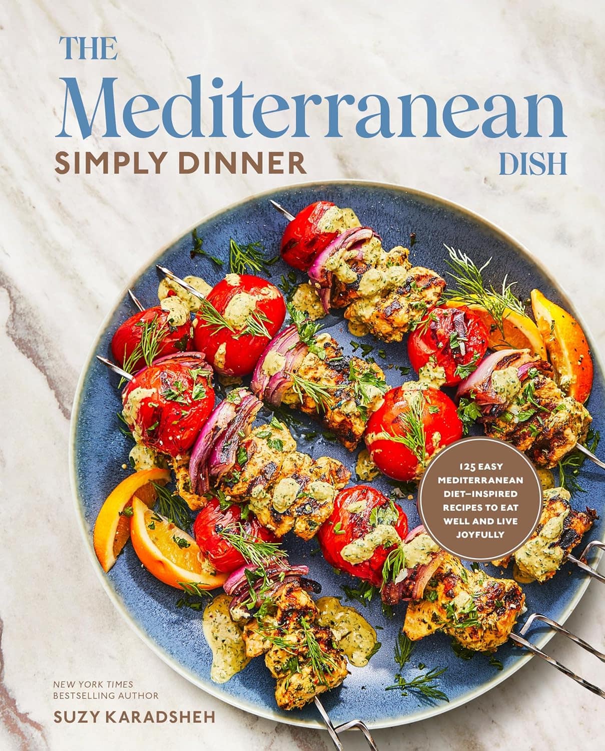 Cover of The Mediterranean Dish: Simply Dinner by Suzy Karadsheh. It shows skewers of grilled vegetables and meat on a plate with garnishes, promoting 125 easy Mediterranean diet-inspired recipes for joyful eating.