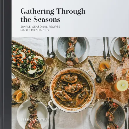 The image features a cookbook titled Gathering Through the Seasons by Jessica Kostka. It shows a spread of various dishes, including a hearty stew in a pot, salads, and decorated table settings, emphasizing seasonal recipes for sharing.